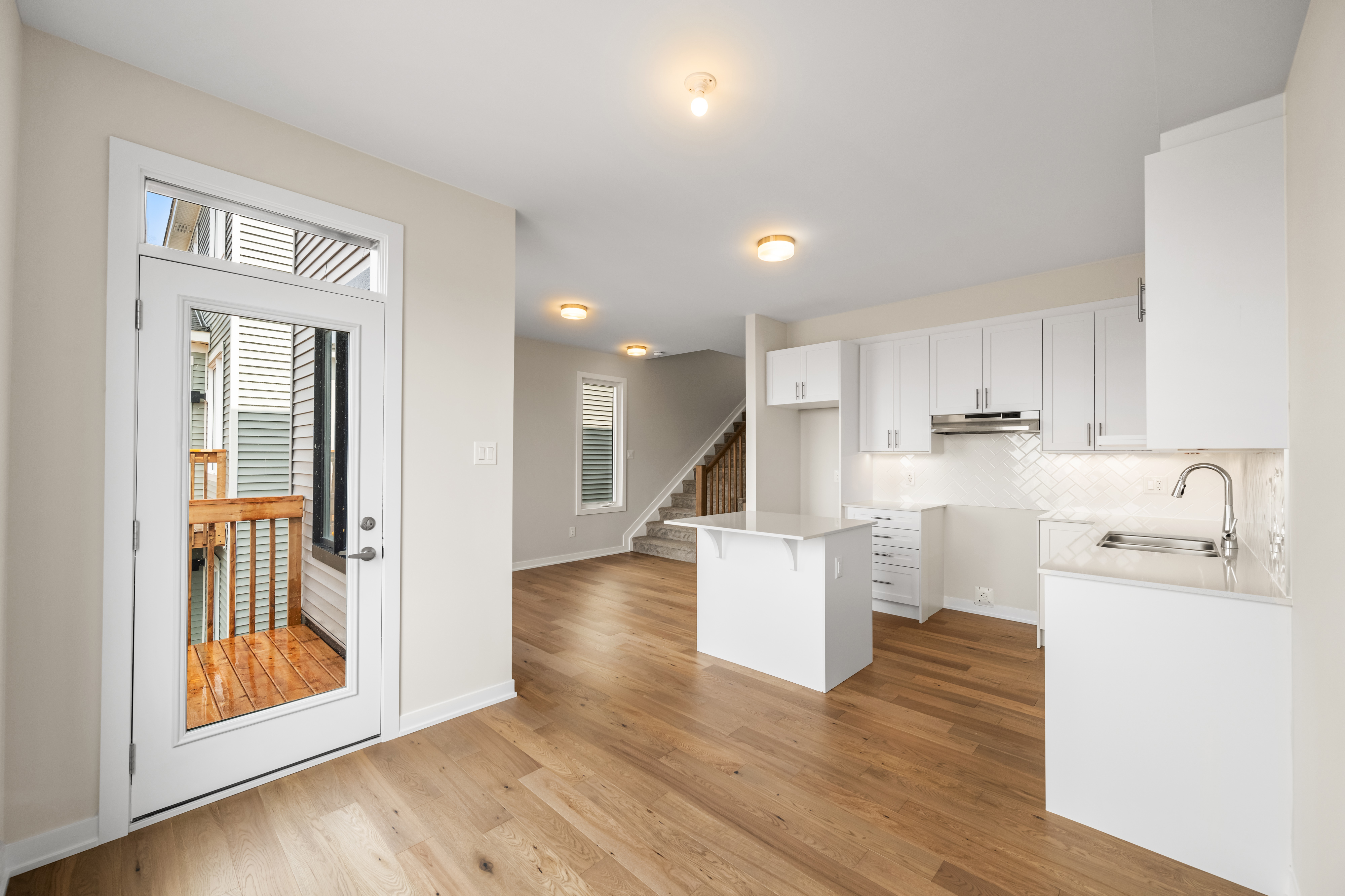 Kitchen with island and herringbone backsplash beside a door to the rear deck