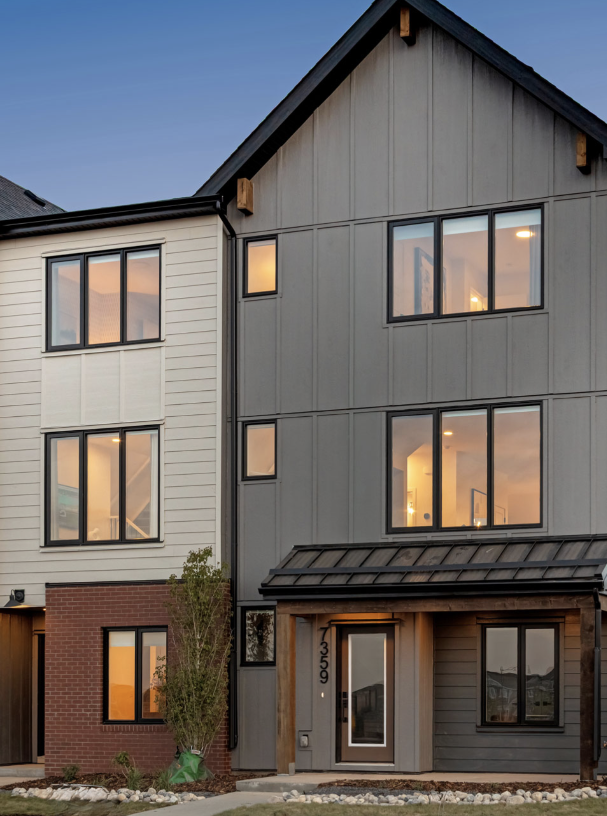 Monocle townhome exterior at dusk with warm interior lighting