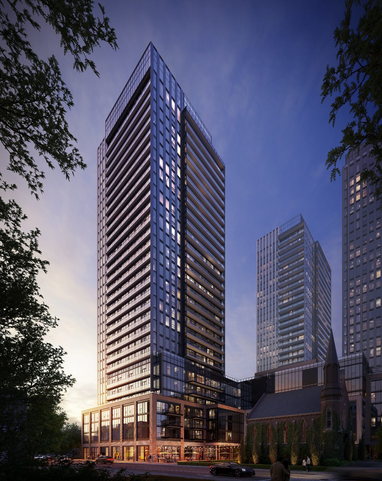 Tower 2 at twilight with glowing street-level retail and the historic church beside it