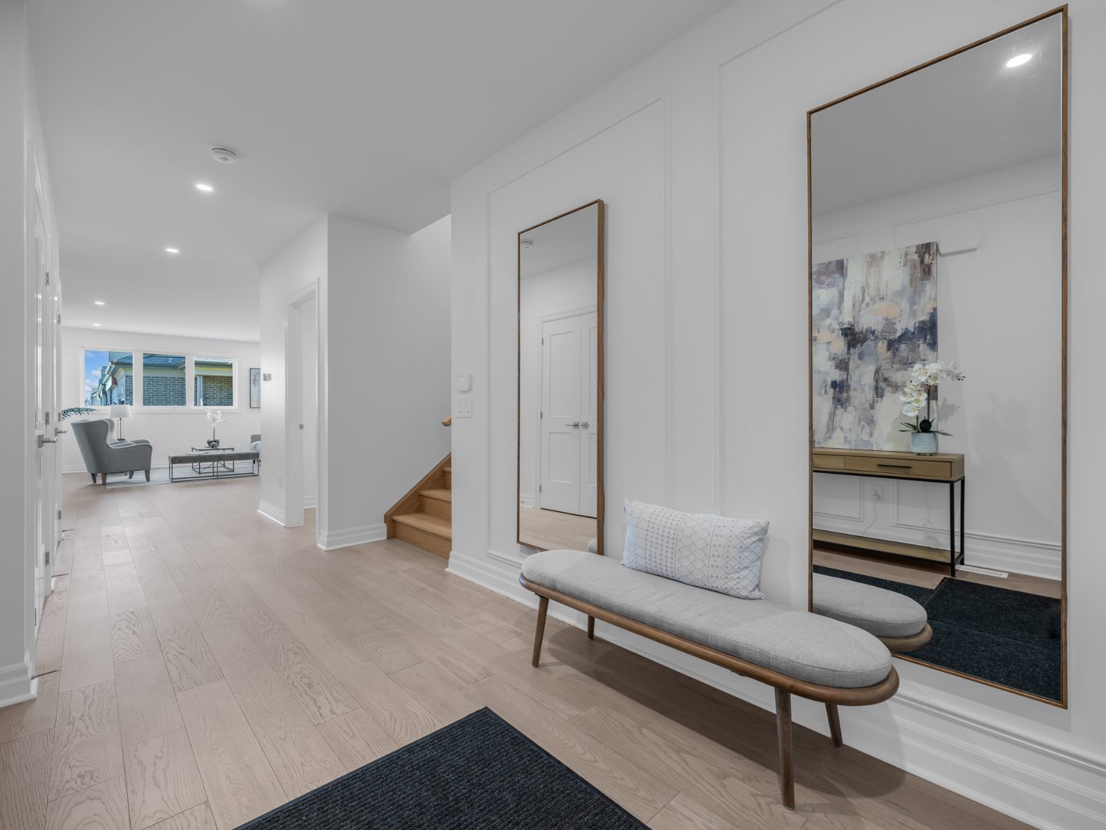 Bright foyer with panelled wall moulding, oak stairs and hardwood leading to a living room