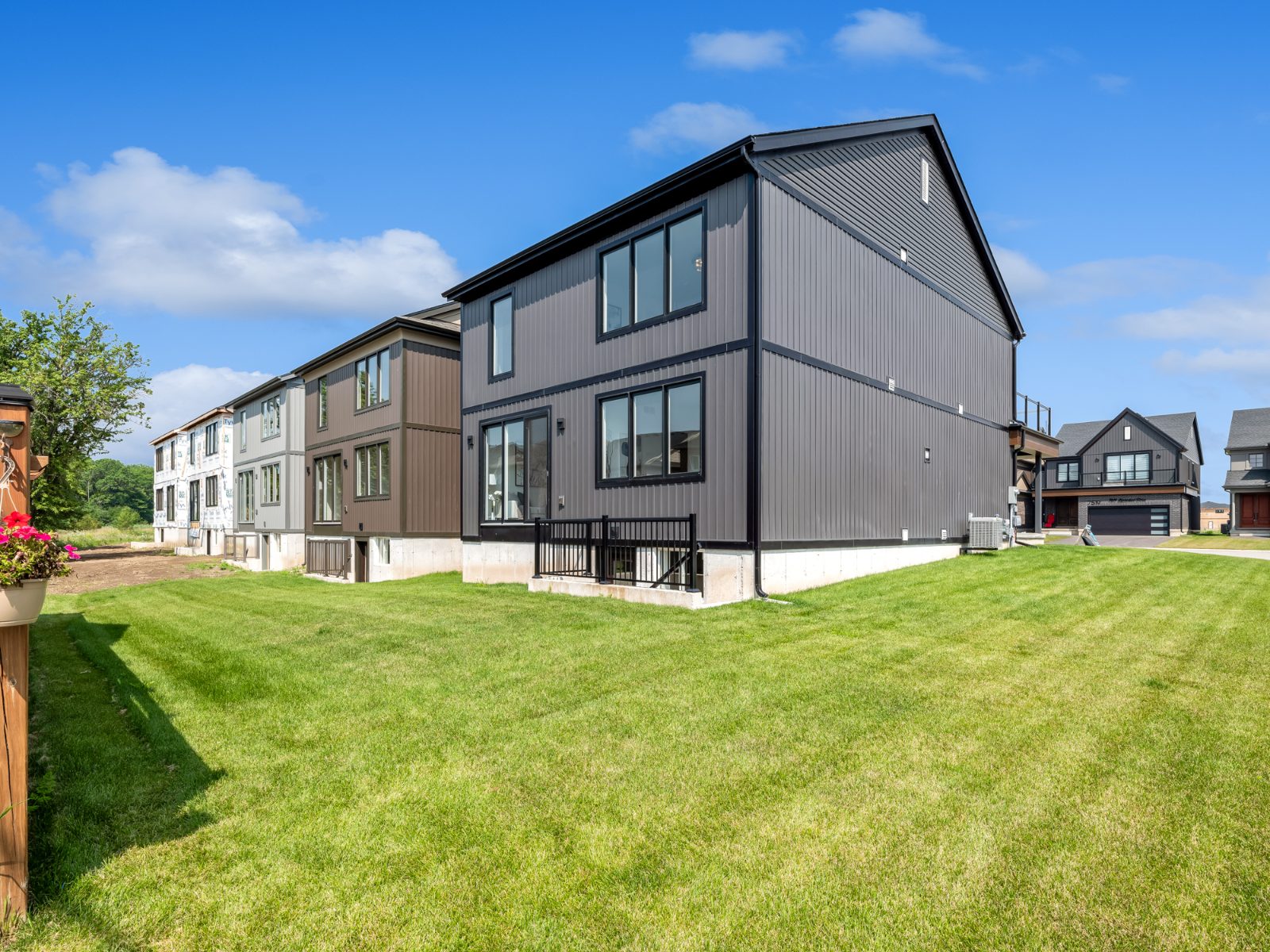 Rear exterior of a modern two-storey Splendour home with dark vertical siding and a large green lawn