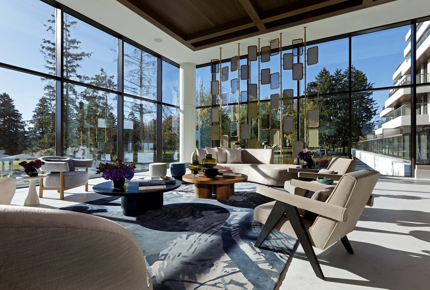 Royal Bayview's completed lobby lounge with floor-to-ceiling windows, sculptural brass screen and designer seating overlooking mature trees