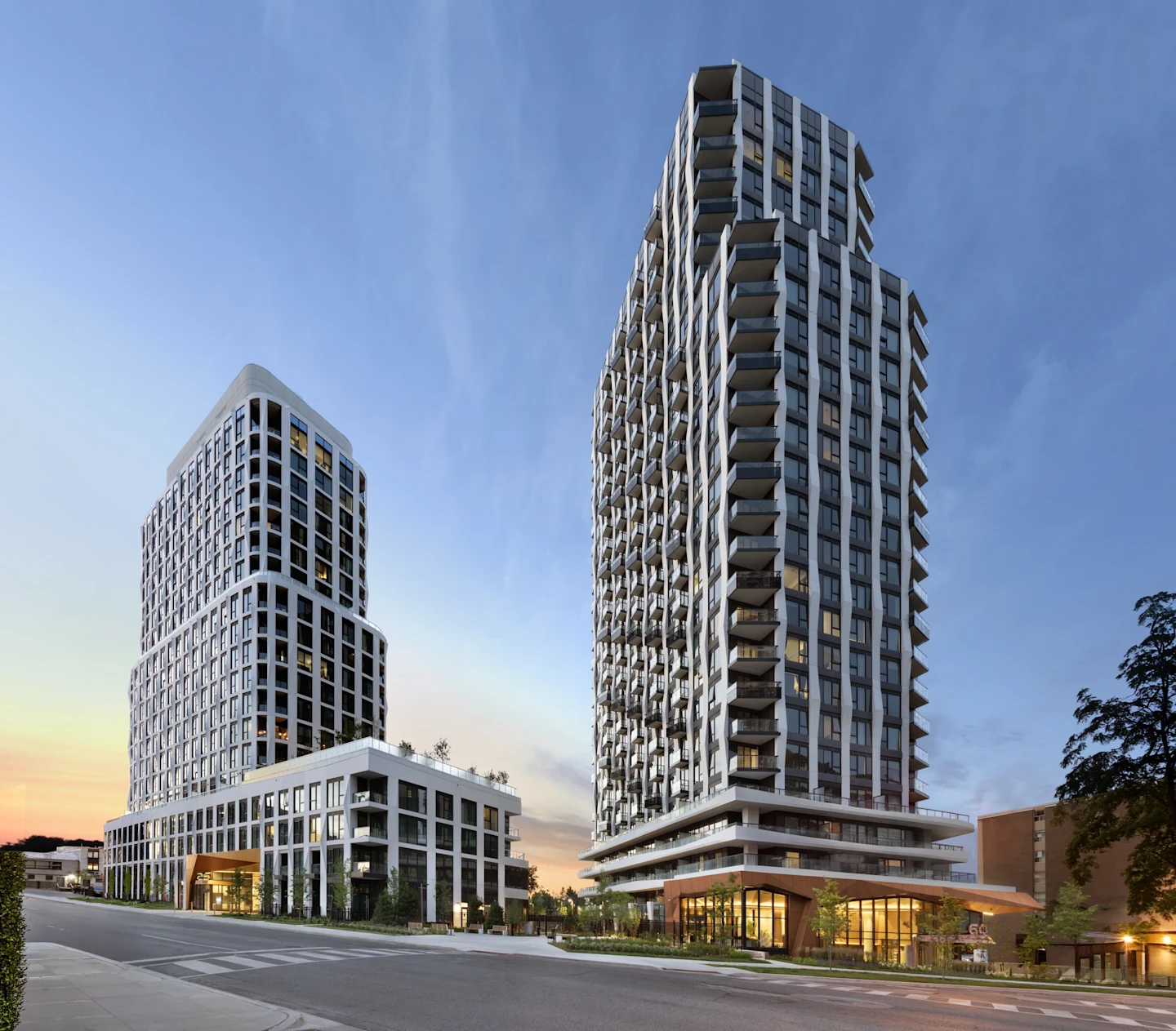 Westerly and Westerly 2, two completed condominium towers in Etobicoke photographed at dusk with glowing ground-floor lobbies