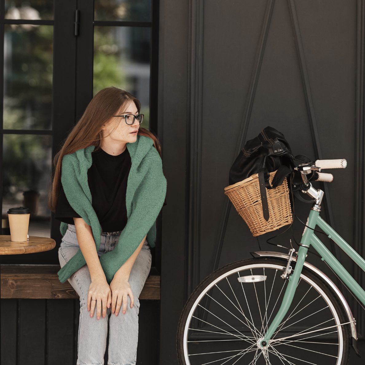 Lifestyle image from the Unionglen brochure: a woman relaxing outside a café beside a mint-green bicycle with a wicker basket
